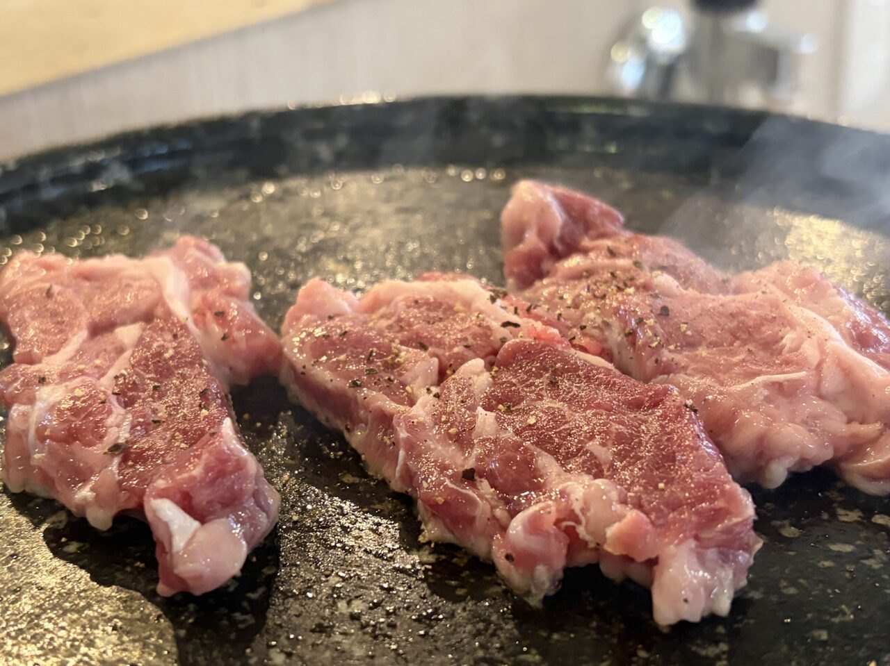 黒い陶板に並べた生ラム。湯気が立っている